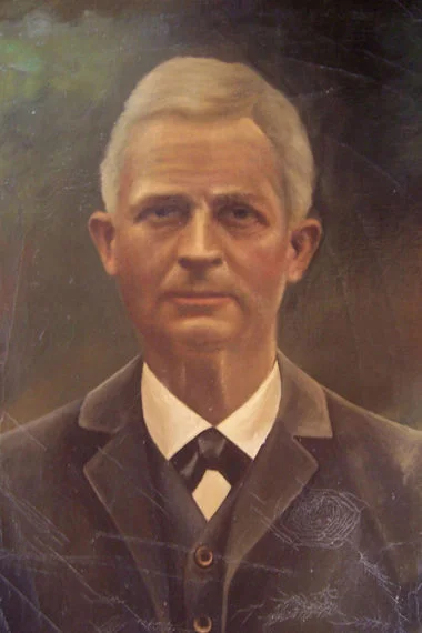 Porträt von Robert Mühle mit grauem, kurzen Haar und einem dunklen Anzug.