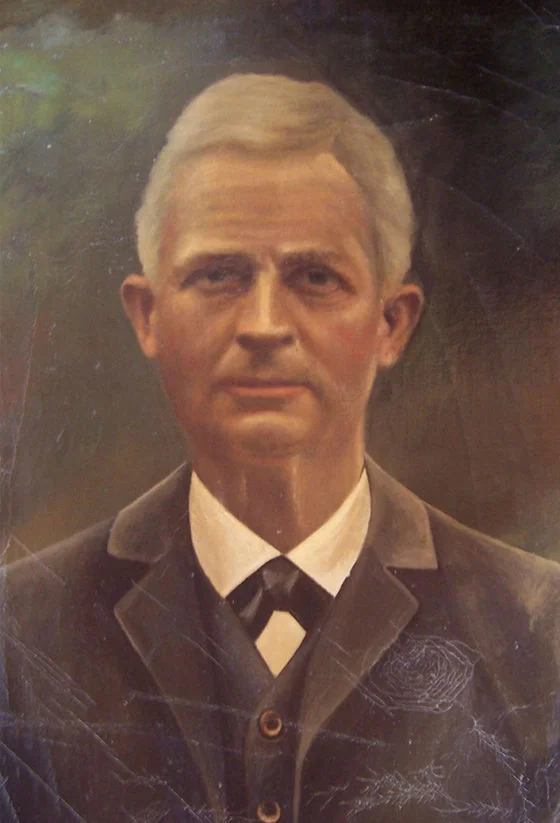 Porträt von Robert Mühle mit grauem, kurzen Haar und einem dunklen Anzug.