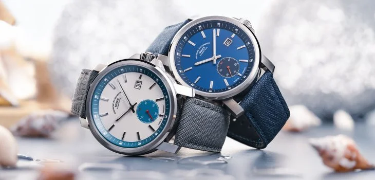 The 29er Big Small Seconds with a stone-white dial and grey strap and the 29er Big Small Seconds with a blue dial and strap are stacked on top of each other on the side.