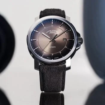 Armbanduhr 29er Casual mit samtbraunem Zifferblatt am grauen Veloursband steht auf einer hell-spiegelnden Oberfläche mit Schattenspiel.