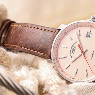 Nahaufnahme der Armbanduhr "29er" mit apricotfarbenem Zifferblatt und braunem Lederband seitlich auf Seilen liegend.