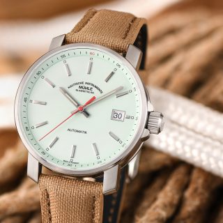 Armbanduhr "29er" mit mint-farbenem Zifferblatt und sandfarbenem Canvasband steht von weißen und braunen Seilen.