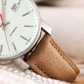 Makroaufnahme der Armbanduhr "29er" mit mintfarbenem Zifferblatt und sandfarbenem Armband liegend auf einem hellen Seil.