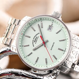 Armbanduhr "29er" mit mintfarbenem Zifferblatt und Metallband liegt seitlich auf einer silbernen Kette.