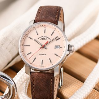 Armbanduhr "29er" mit apricotfarbenem Zifferblatt am braunen Lederband steht auf Holzbrettern und Seilen.
