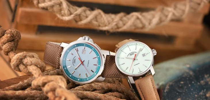 Two maritime wristwatches, one with a light blue and the other with a mint-colored dial, on light brown canvas straps, lie on different ropes.