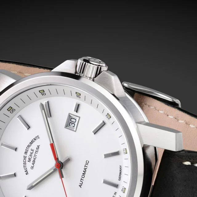 Nahaufnahme der Armbanduhr "29er Big" mit weißem Zifferblatt am schwarzen Lederband und Fokus auf den Flankenschutz.