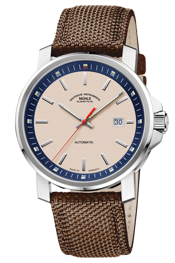 29er Big: Frontalansicht einer Armbanduhr mit sandfarbenem Zifferblatt, nautikblauem Rehaut und silbernem Gehäuse am braunen Canvasband.