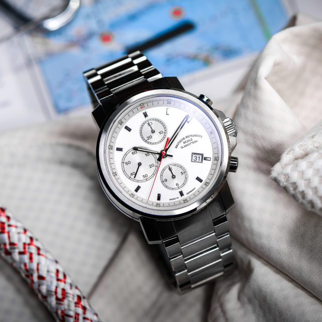29er Chronograph mit weißem Zifferblatt und Metallband liegt auf hellem Stoff.