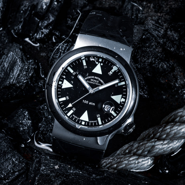 S.A.R. Rescue-Timer: Ein Armbanduhr mit schwarzem Zifferblatt, weißen Indizes, mattsilbernem Gehäuse und schwarzem Band liegt auf dunklen Seilen.