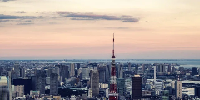 Luftaufnahme von Tokio. Viele Gebäude und ein Turm. Im Hintergrund ein Himmel bei Abendlicht.