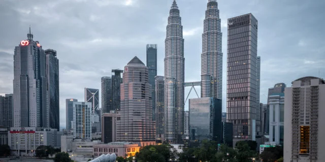 Skyline von Kuala Lumpur mit mehreren Hochhäusern vor grauem Himmel