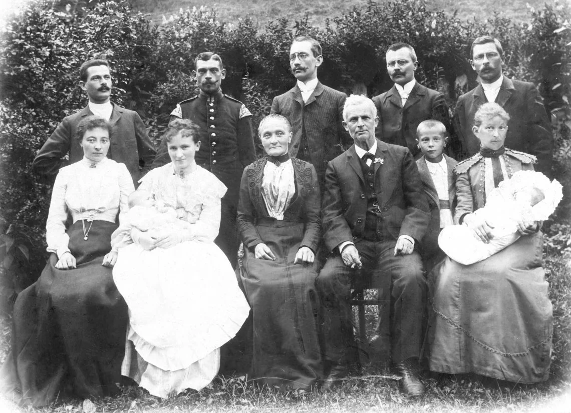 Altes Schwarz-Weiß-Foto mit Männern in Anzügen, Frauen in Kleidern und Kindern.