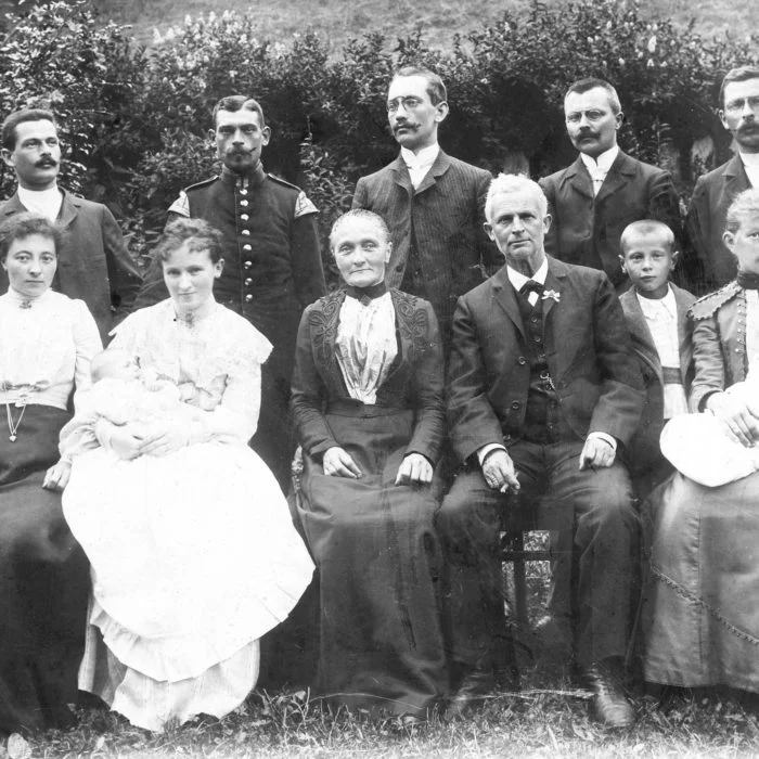 Altes Schwarz-Weiß-Foto mit Männern in Anzügen, Frauen in Kleidern und Kindern.