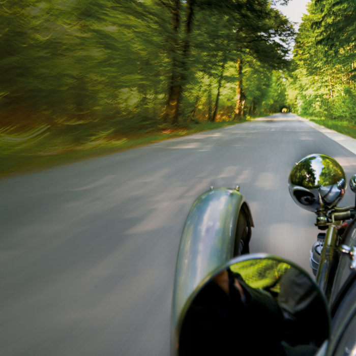 Oldtimer fährt auf einer Waldstraße