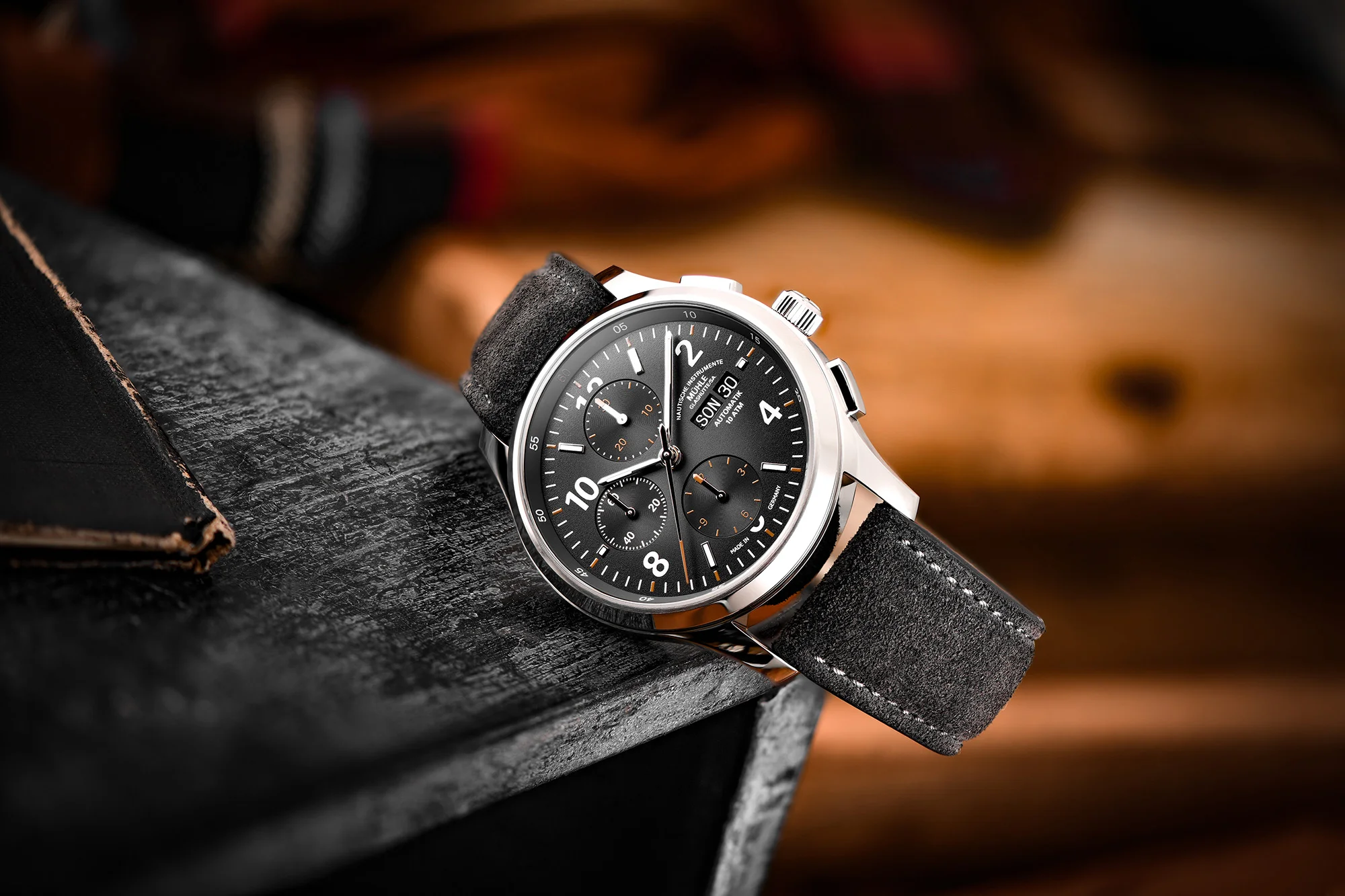 Armbanduhr Lunova Chronograph am grauen Veloursband liegt auf einer schwarzen Holzkiste.