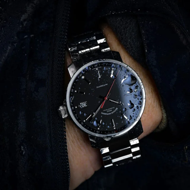 Armbanduhr 29er mit schwarzem Zifferblatt am Metallband wird am Handgelenk getragen.