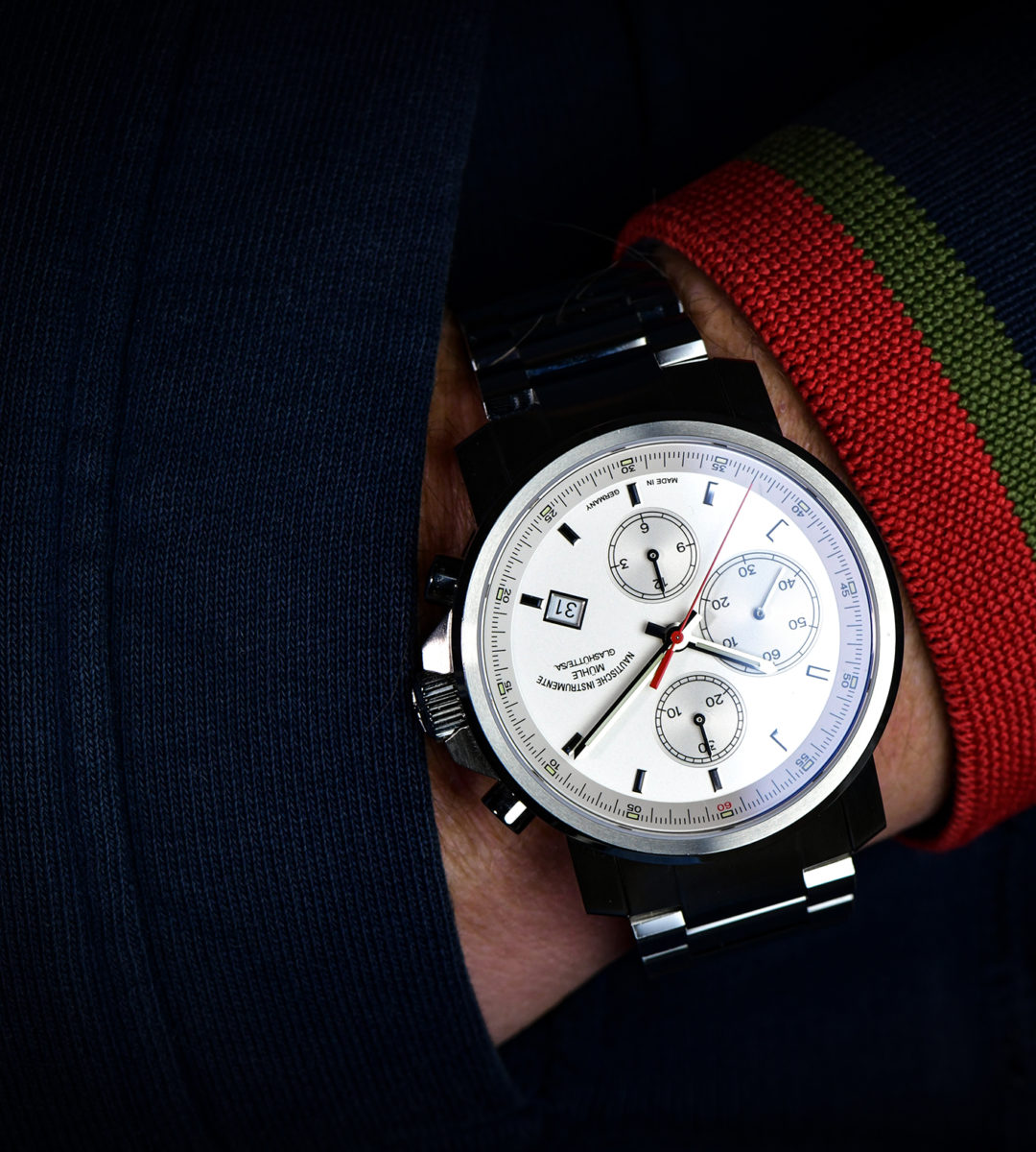 29er Chronograph mit weißem Zifferblatt am Metallband wird am Handgelenk getragen.
