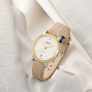 Armbanduhr Teutonia IV Lady mit weißem Zifferblatt, Bicolor-Gehäuse und beigem Veloursband steht auf einer hellen Damenjacke.