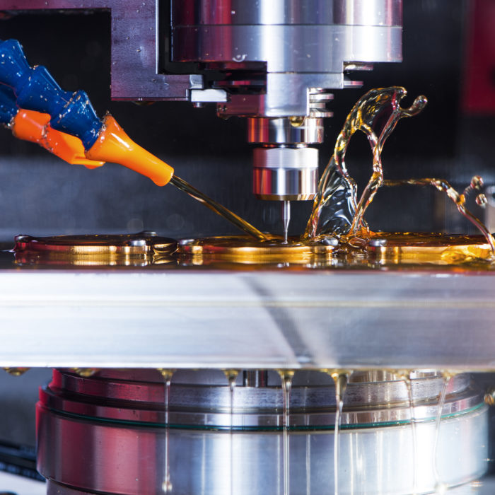 Nahaufnahme der CNC-Fertigung: Ein Werkzeug bearbeitet eine Metallplatte, Wasser spritzt nach oben.