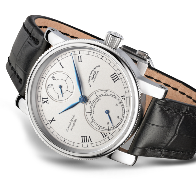 Robert Mühle Auf/Ab: Armbanduhr mit weißem Zifferblatt, blauen Zeigern, silbernem Gehäuse und schwarzem Lederband.