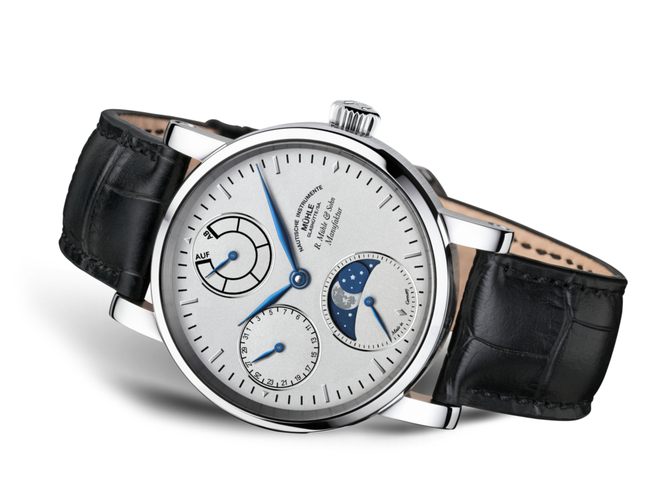 Liegende Armbanduhr mit weißem Zifferblatt, drei Hilfszifferblättern, blauen Zeigern, silbernem Gehäuse und schwarzem Lederband vor weißem Hintergrund.
