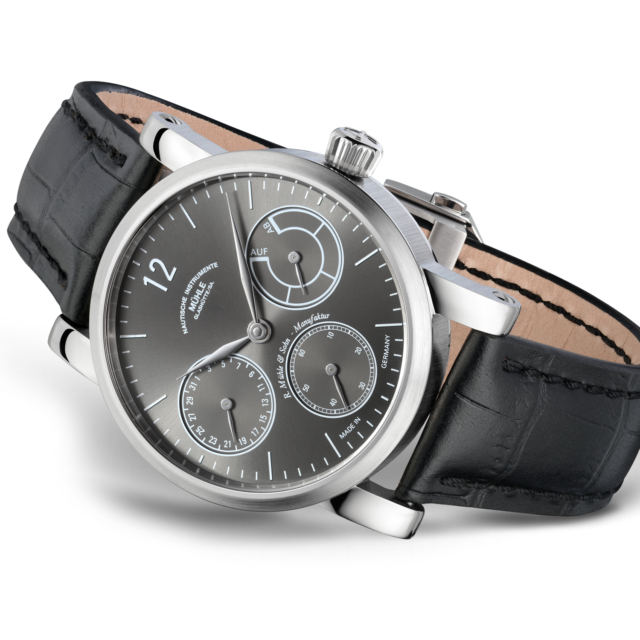 Robert Mühle Zeigerdatum: Armbanduhr mit grauem Zifferblatt, drei Hilfszifferblättern, silbernen Zeigern und Gehäuse, schwarzes Lederband.