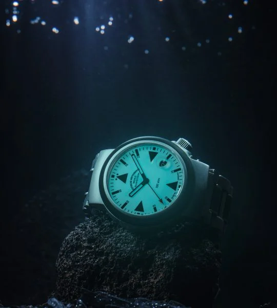 S.A.R. Rescue-Timer Lumen am Metall-/Kautschukband liegt unterWasser auf einem Stein.