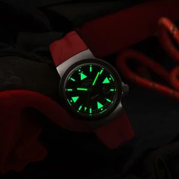 Nachtaufnahme des S.A.R. Rescue-Timer am roten Kautschukband mit grün nachleuchtenden Indizes.