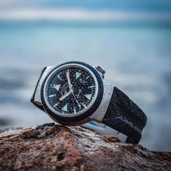 Nasser S.A.R. Rescue-Timer on a black rubber strap lies on a rock in front of the sea.
