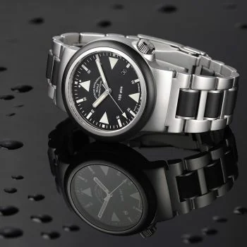 S.A.R. Rescue-Timer mit schwarzem Zifferblatt am Metall-/Kautschukband liegt seitlich auf einer schwarz-spiegelnden Oberfläche mit Wassertropfen.