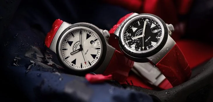 Zwei Armbanduhren (S.A.R. Rescue-Timer LUMEN und S.A.R. Rescue-Timer) an roten Kautschukbändern liegen seitlich auf blau-roter Einsatzkleidung.