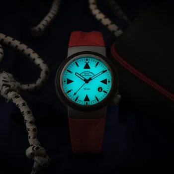 Nachtansicht des S.A.R. Rescue-Timer LUMEN mit rotem Kautschukband und blau-grün nachleuchtendem Zifferblatt