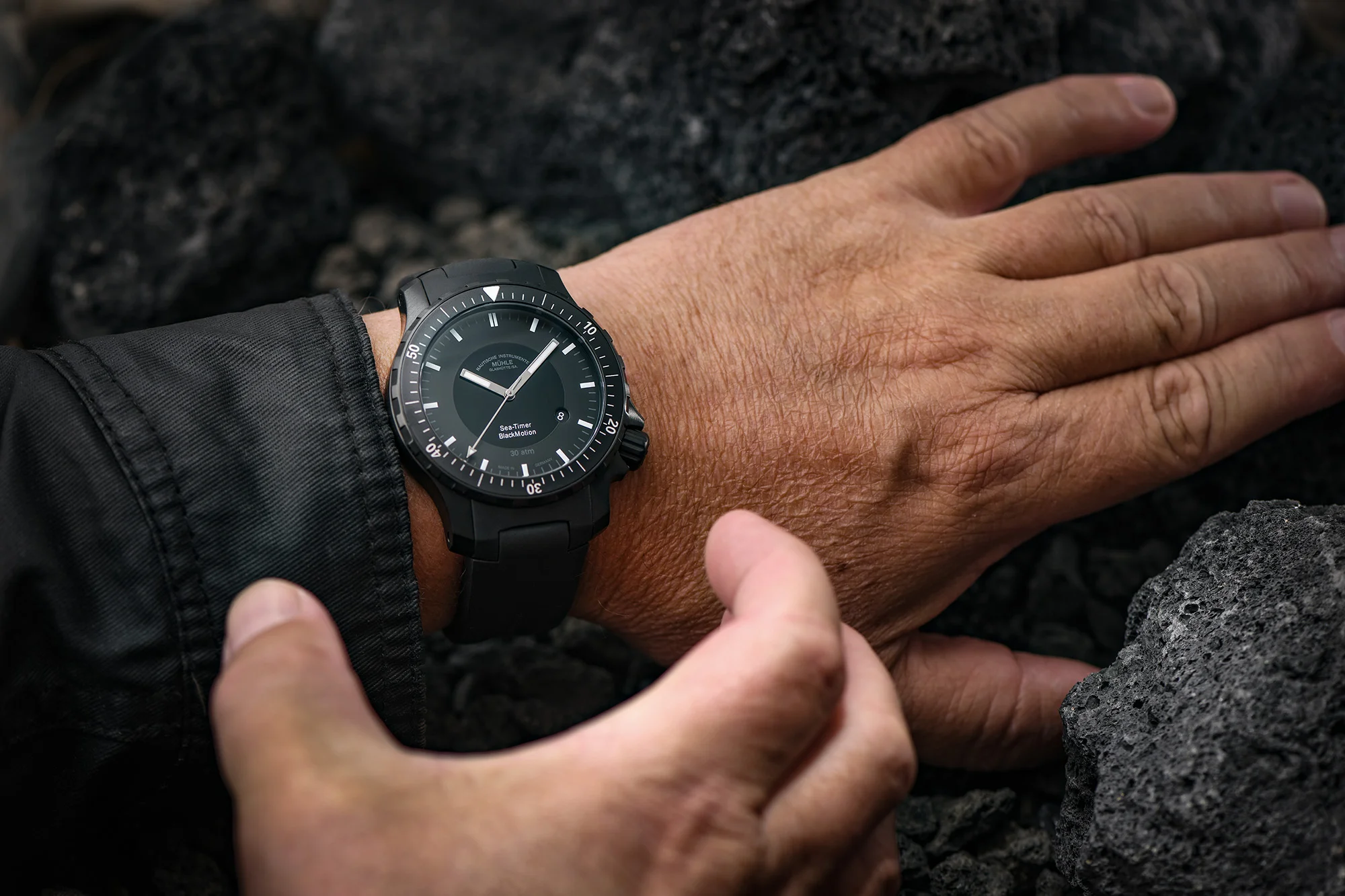 Armbanduhr "Sea-Timer BlacMotion" wird am Handgelenk getragen. Eine zweite Hand greift nach der Uhr.