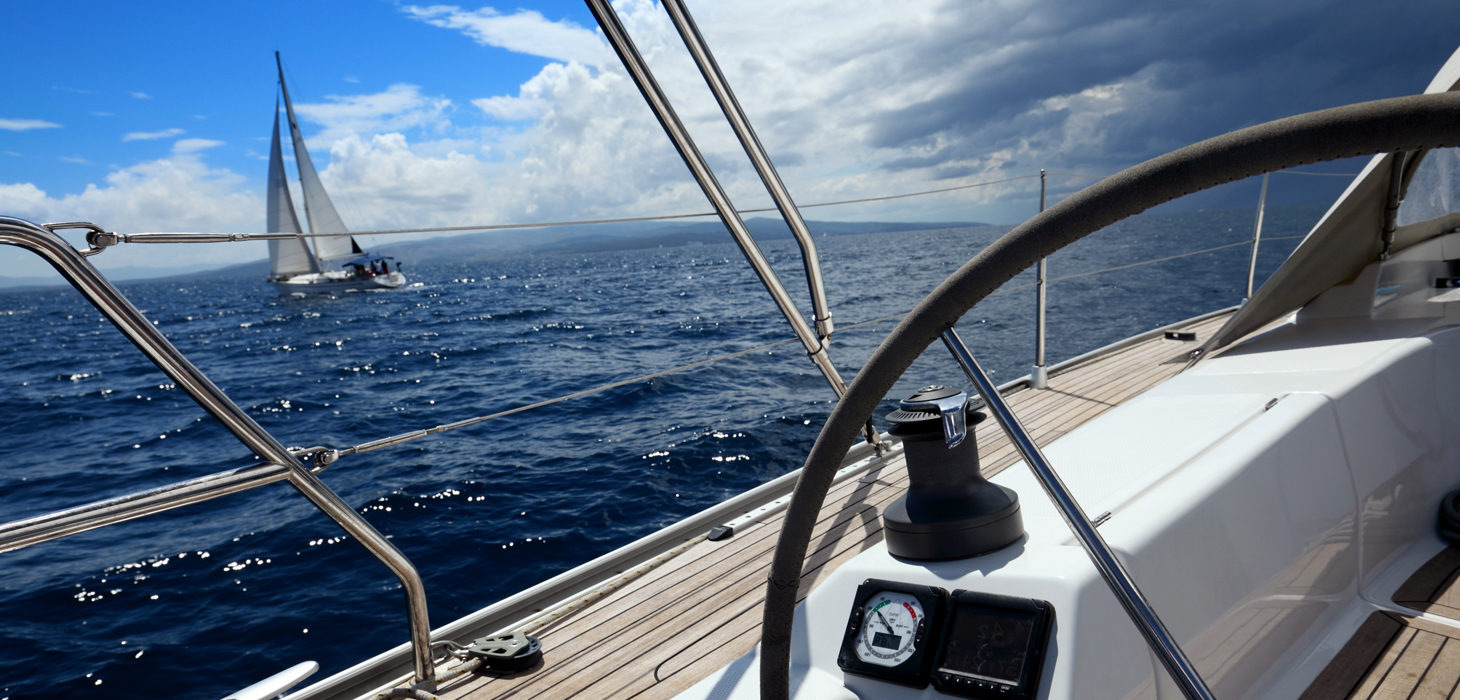 Anschnitt eines Segelbootes im Sonnenschein, am Horizont aufkommendes Unwetter