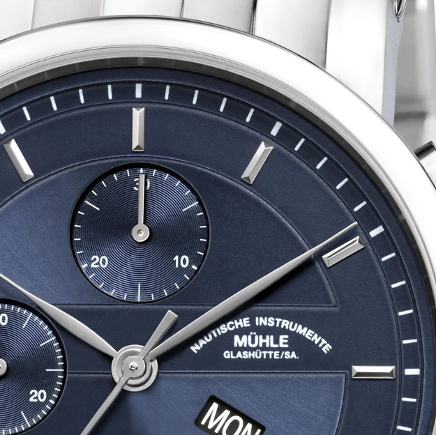 Detailaufnahme des Teutonia II Chronograph mit blauem Zifferblatt am Metallband mit Fokus auf das Zifferblatt zwischen 12 und 3 Uhr.