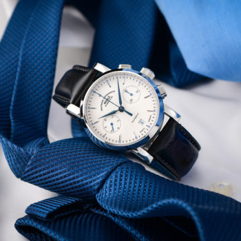 Armbanduhr Teutonia IV Chronograph am schwarzen Lederband liegt schräg auf einer blauen Krawatte.
