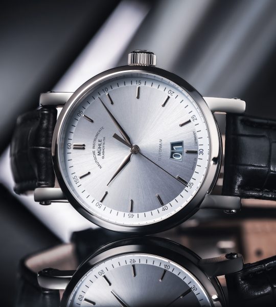 Armbanduhr Teutonia IV Grodatum Edition 1994 mit eisblauem Zifferblatt am schwarzen Lederband liegt seitlich auf einer grauen-spiegelnden Oberfläche.