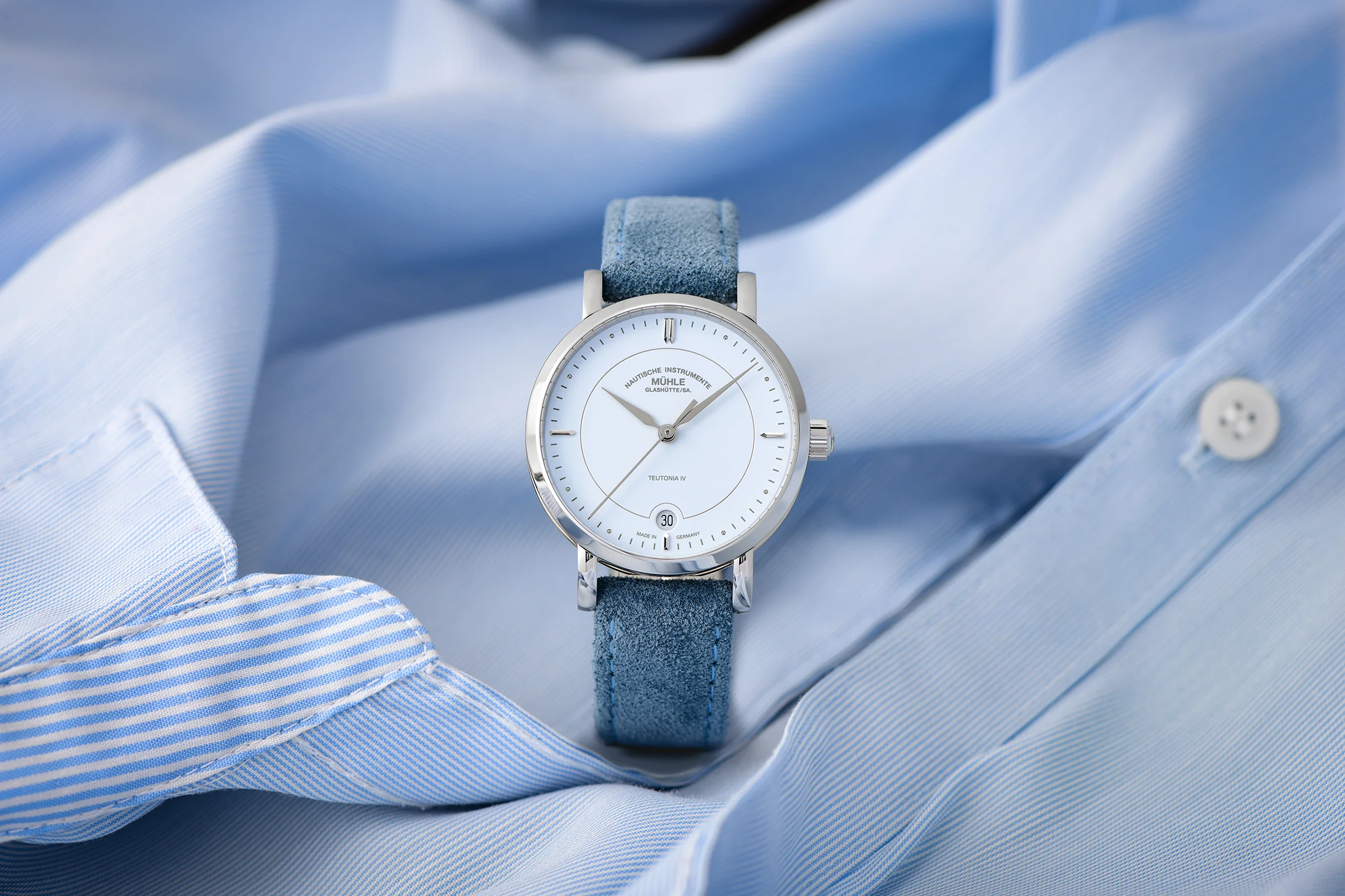 Armbanduhr Teutonia IV Lady mit pastellblauem Zifferblatt am blauen Veloursband steht auf einer hellblauen Damenbluse.