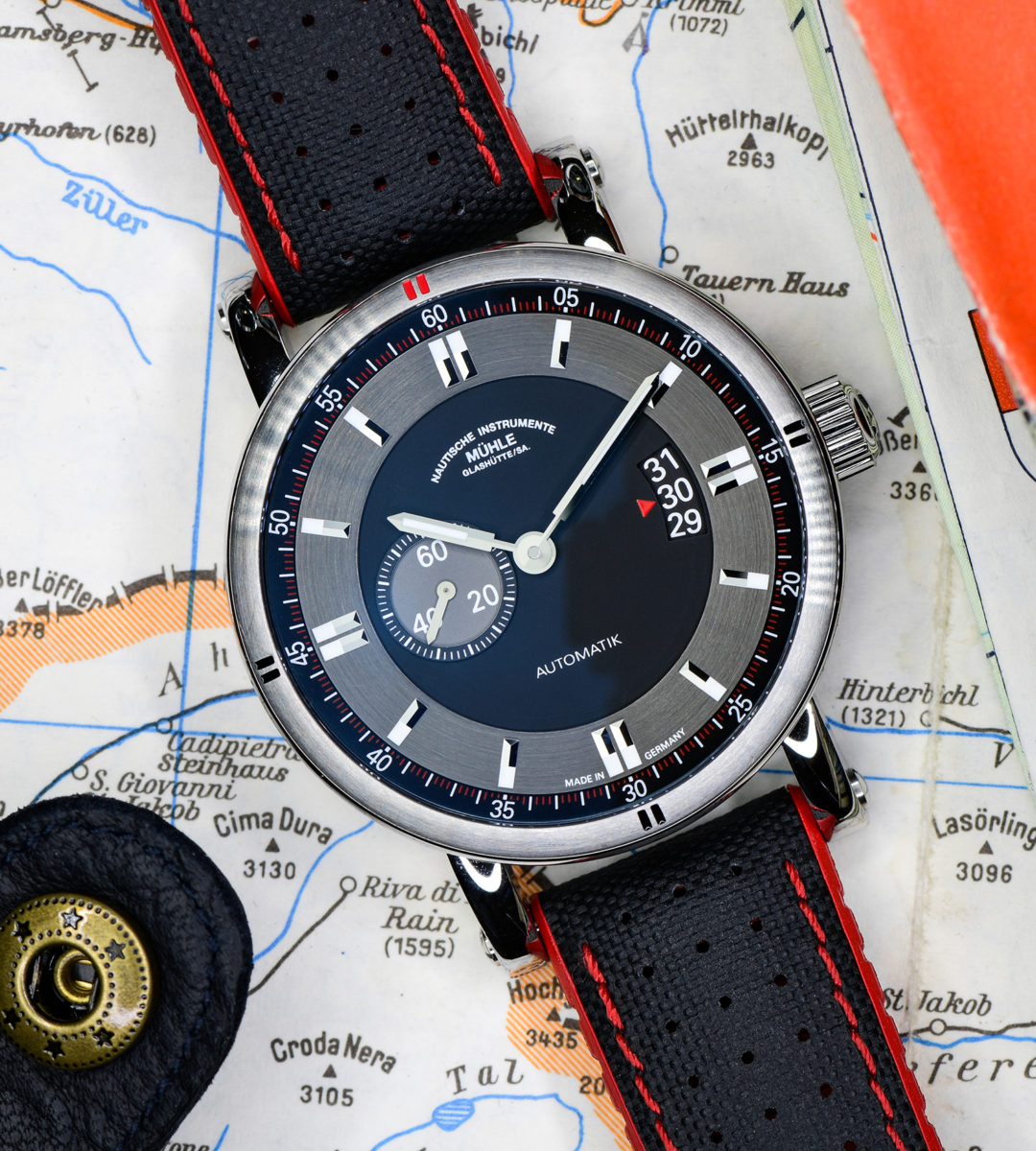 Armbanduhr Teutonia Sport II am schwarz-roten Leder-Kautschukband liegt auf einer Landkarte.