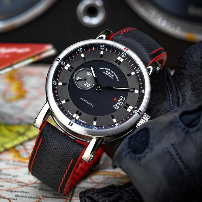 Teutonia Sport II, eine Uhr mit schwarzem Zifferblatt und roten Details, steht schräg auf einer Landkarte.