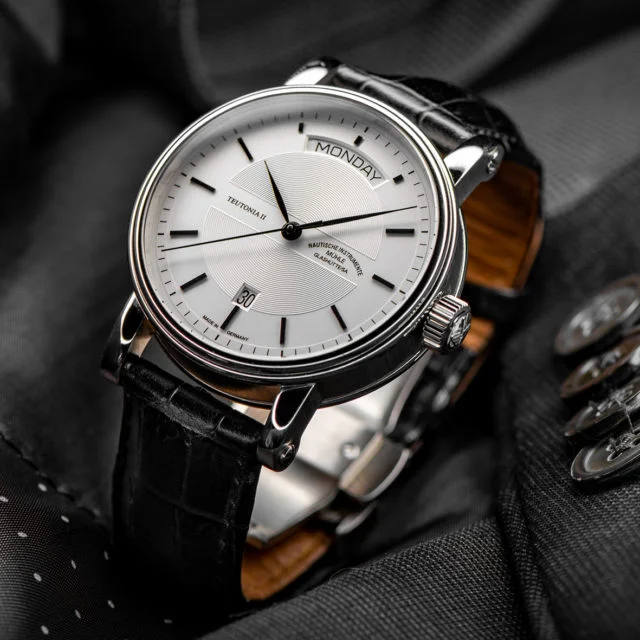 Armbanduhr Teutonia II Tag/Datum am schwarzen Lederband steht auf einem grauen Sakko.