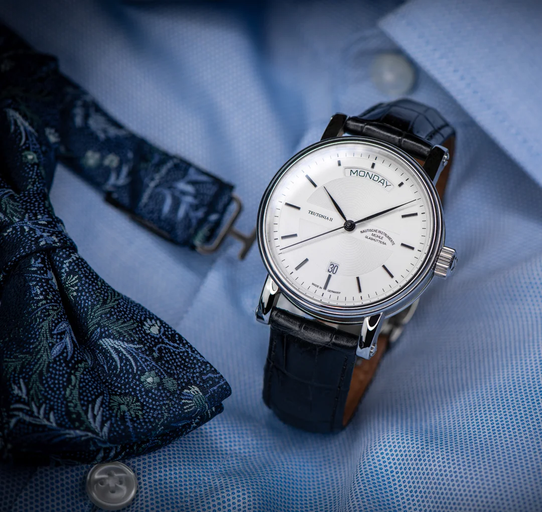 Armbanduhr Teutonia II Tag/Datum am schwarzen Lederband steht auf einem hellblauen Herrenhemd.