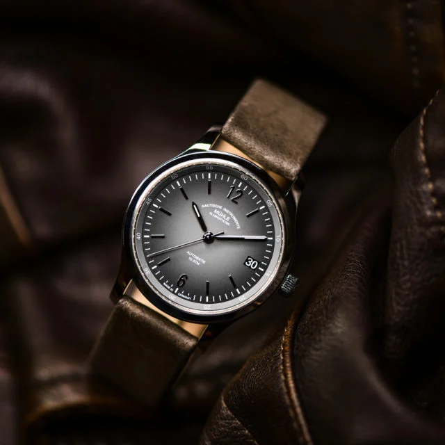 Armbanduhr Lunova Lady am grauen Lederband steht auf einer braunen Lederjacke.