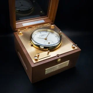 Quarz-Marinechronometer Edition 1994 mit weißem Zifferblatt, Messingplakette und Holzbox mit Sichtfenster.