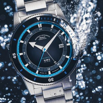 Sportivo Travel GMT – eine Armbanduhr mit schwarz-grauem Zifferblatt, schwarzer Lünette, silbernem Gehäuse und Stahlband – unter Wasser mit Luftblasen
