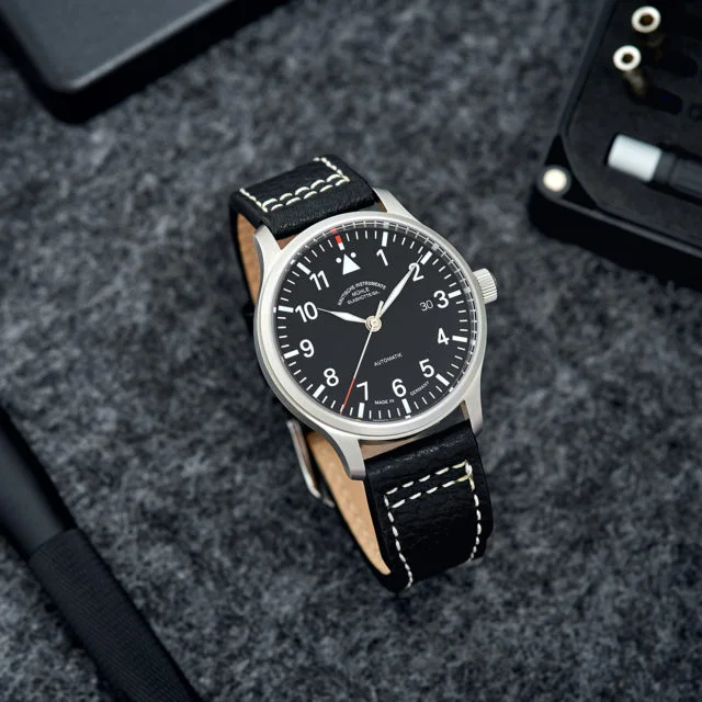 Armbanduhr Terrasport II mit schwarzem Zifferblatt und schwarzem Lederband steht auf einer grau-melierten Oberfläche.