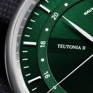 Nahaufnahme des grünen Zifferblatts und silbernen Gehäuses der Teutonia II GMT mit Fokus auf den linken Rand und die applizierten Indizes.