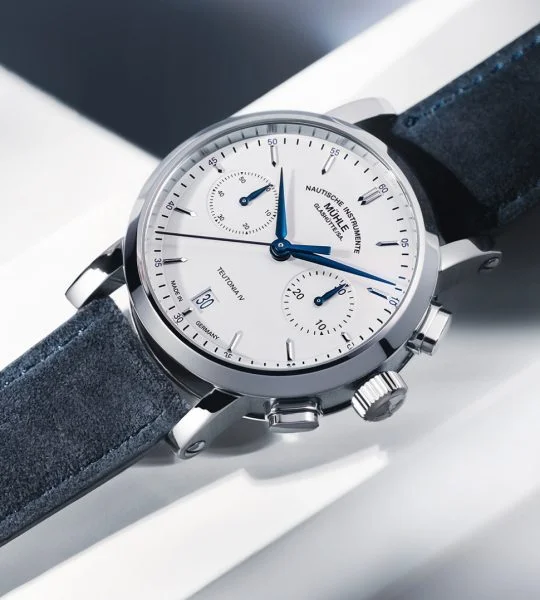 Armbanduhr Teutonia IV Chronograph mit weißem Zifferblatt, silbernem Gehäuse und blauem Velourslederband liegt auf einem weißen Untergrund.