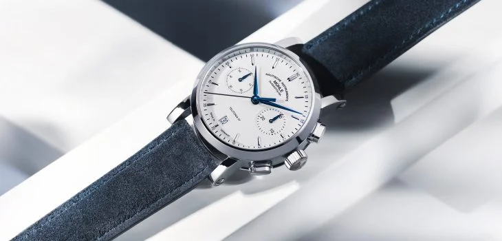 Armbanduhr Teutonia IV Chronograph mit weißem Zifferblatt, silbernem Gehäuse und blauem Velourslederband liegt auf einem weißen Untergrund.
